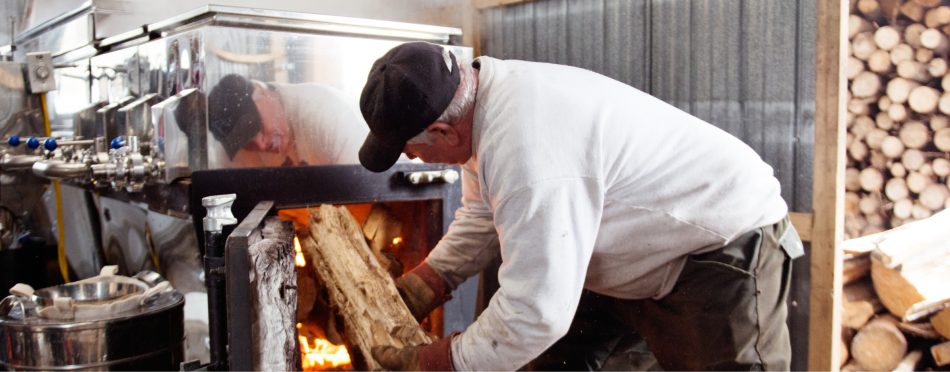 A worker putting wood in an oven